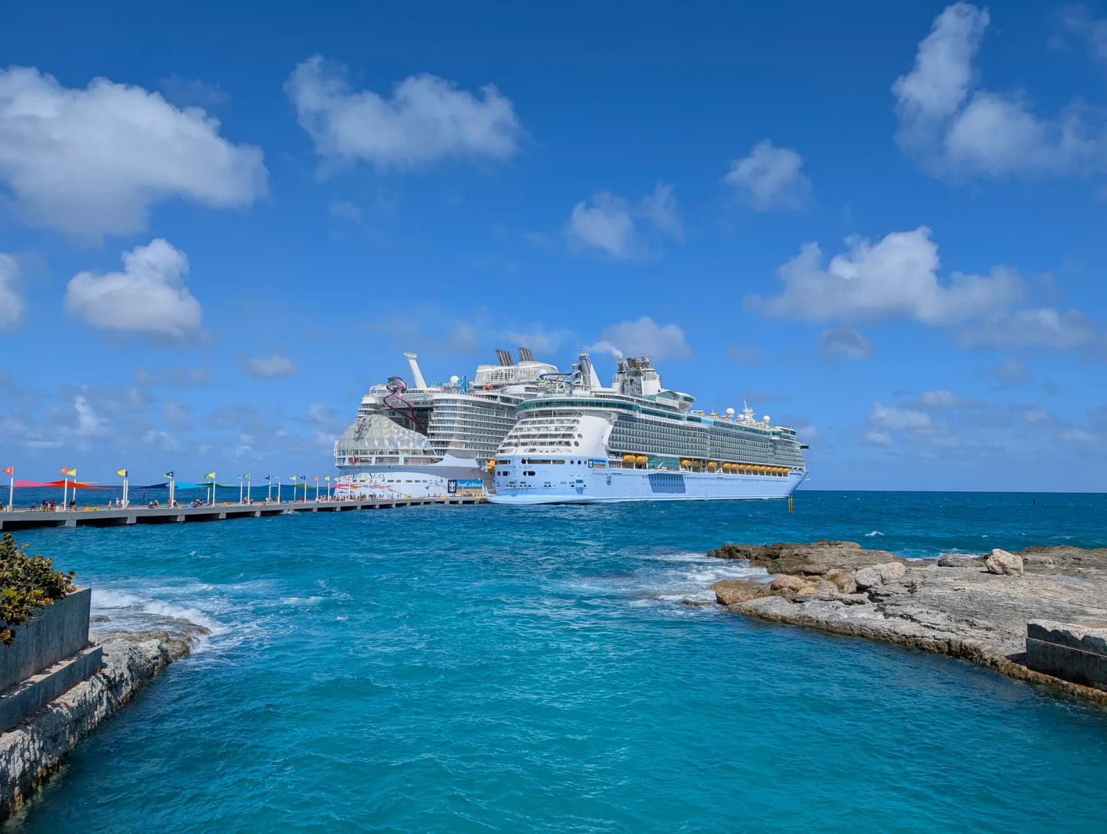 Two Royal Caribbean ships, Wonder of the Seas and Freedom of the Seas, docked side by side at the pier at Perfect Day at CocoCay under a blue sky