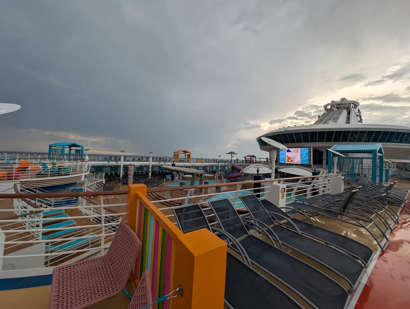 Rows of empty loungers on the pool deck of Royal Caribbean's Adventure of the Seas under a cloudy sky