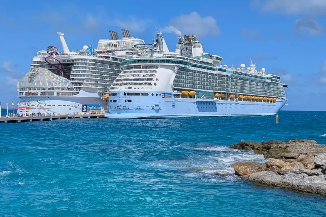 Royal Caribbean's Wonder of the Seas and Freedom of the Seas docked side by side at the pier at Perfect Day at CocoCay, The Bahamas, under a blue sky