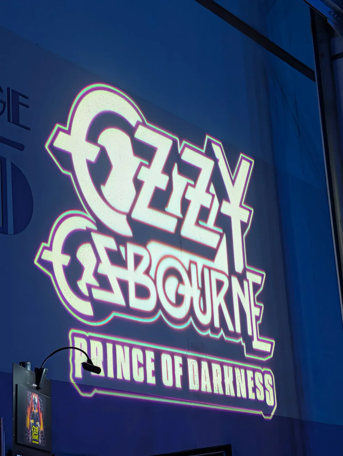 The Ozzy Osbourne: Prince of Darkness logo projected in white and purple on the side of a soundstage